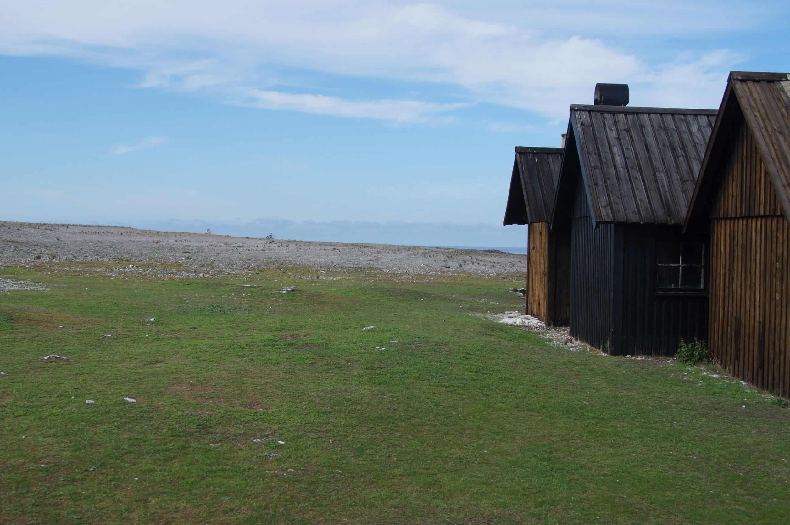 Image of a three fishing huts with barren coast in the background