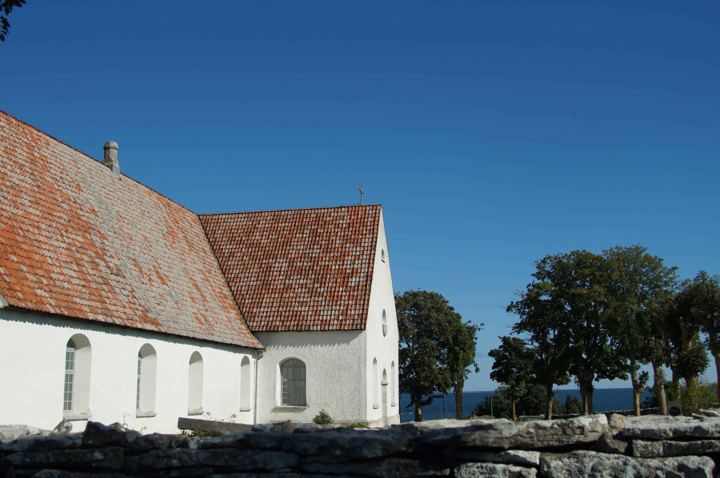 Image of a church building with some trees and the sea in the background